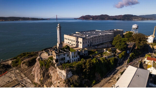 Alcatraz Island at sunset with prison buildings and an American flag in the foreground