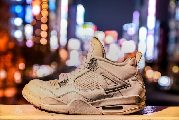 Air Jordan 4 White Cement sneakers on concrete with urban skyline in the background