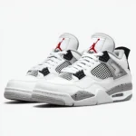 Air Jordan 4 White Cement sneakers on concrete with urban skyline in the background