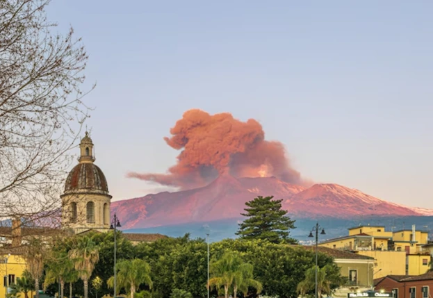 Mount Etna erupting with ash clouds and glowing lava as tourists observe from a safe distance