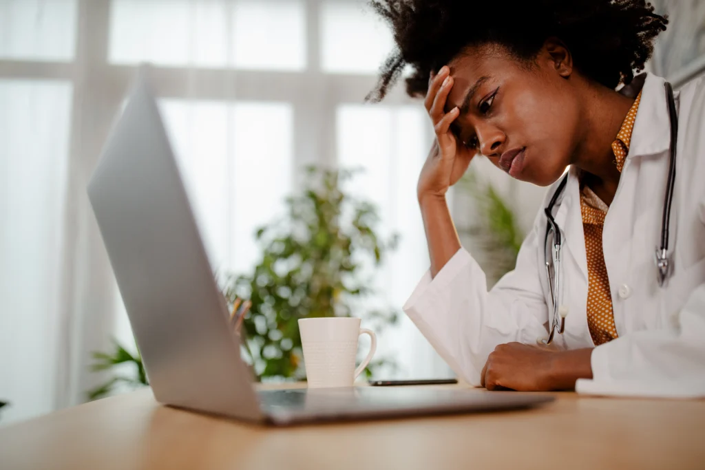 A stressed person sitting in front of multiple digital screens, overwhelmed by notifications and digital devices.