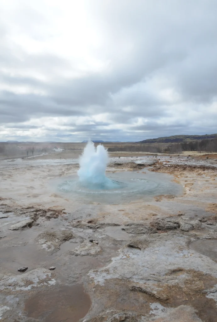 Hydrothermal eruption at Black Diamond Pool in Yellowstone National Park, releasing steam and debris into the air.