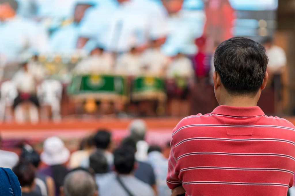 César Chávez portrait with a backdrop of protest signs and headlines highlighting the 2026 allegations, symbolizing a reevaluation of his legacy