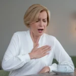 Person holding their chest while laughing and coughing, symbolizing concerns about high blood pressure triggers
