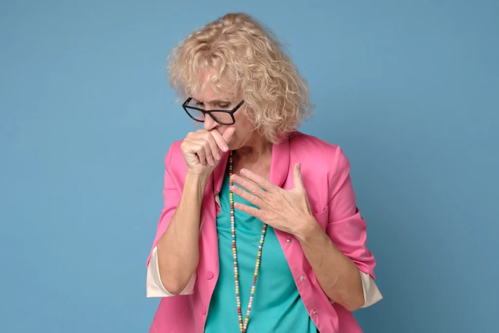 Person holding their chest while laughing and coughing, symbolizing concerns about high blood pressure triggers
