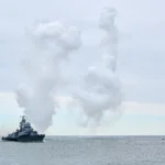 U.S. Navy destroyer at sea during an operational mission with smoke visible in the distance, illustrating an incident report analysis scenario.