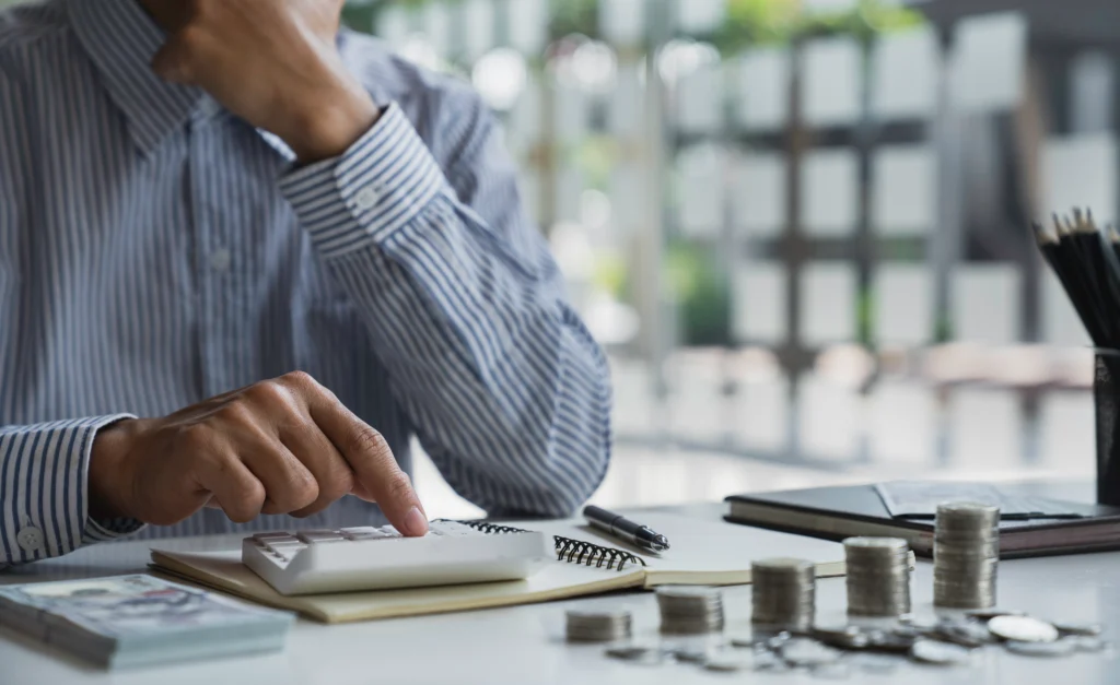 A person managing personal finances with a laptop, calculator, and budget planning notes on a desk representing financial discipline and money management
