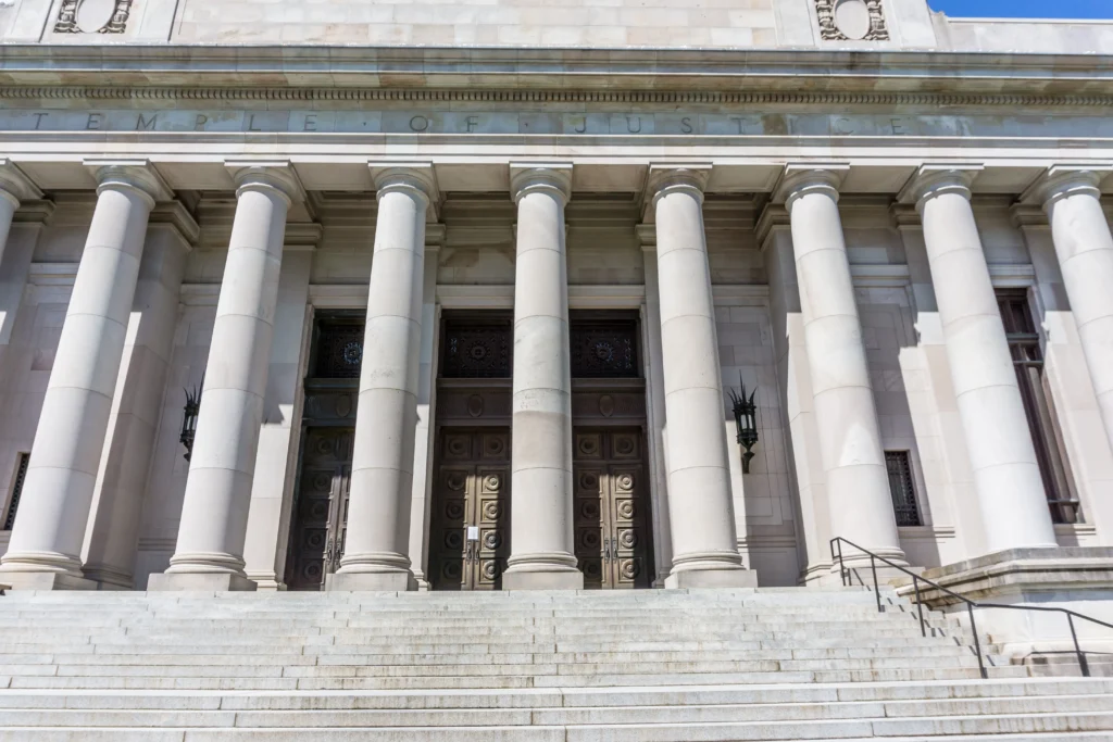 Courtroom scene illustrating the events leading up to the Hannah Dugan ICE case decision, featuring a judge's bench, legal documents, federal agents, and attorneys discussing immigration enforcement actions.