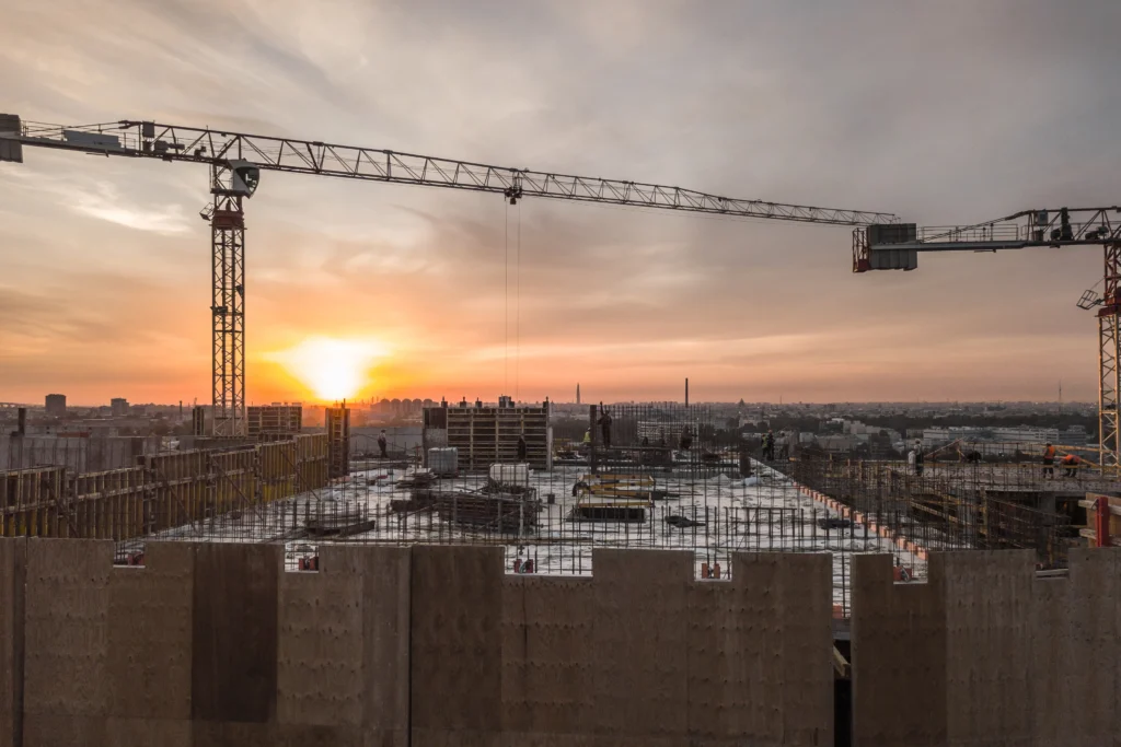Affordable housing construction in New York with apartment buildings, cranes, and the Manhattan skyline in the background.